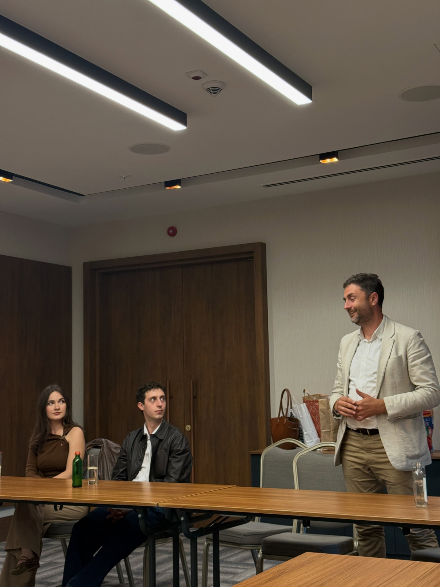A guest speaker addressing members seated at meeting tables during a club session.